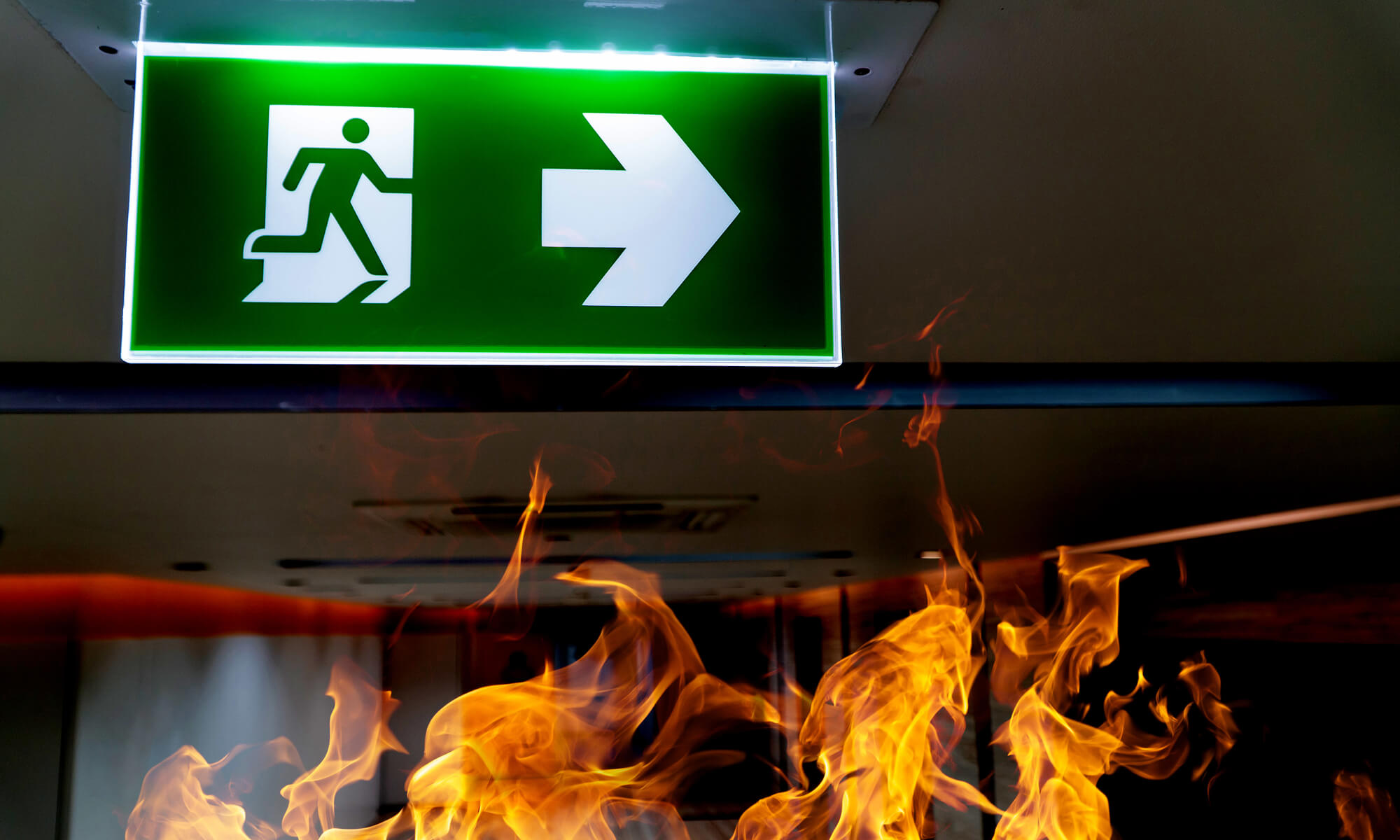 Green fire escape sign hang on the ceiling in the office.