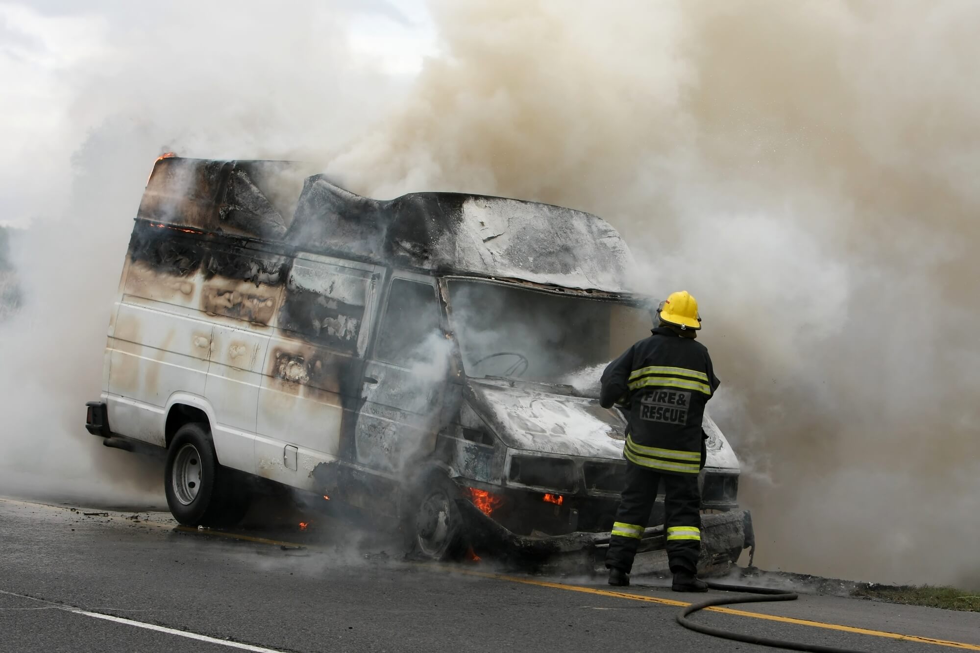 Fireman putting out burning van on the side of the road