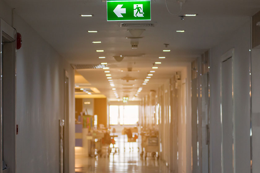 Green emergency exit sign in hospital showing the way to escap
